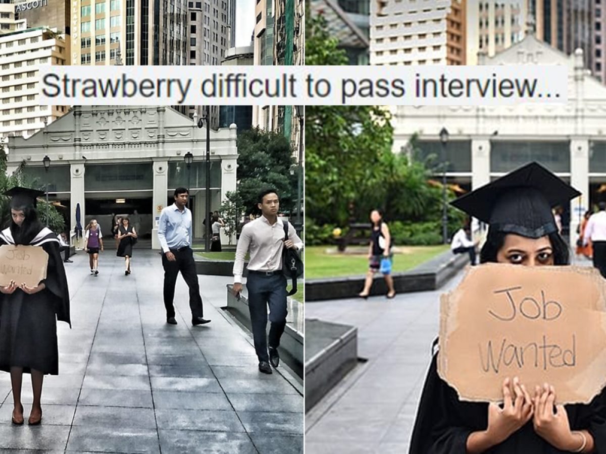 university graduate holds “job wanted” sign at raffles place