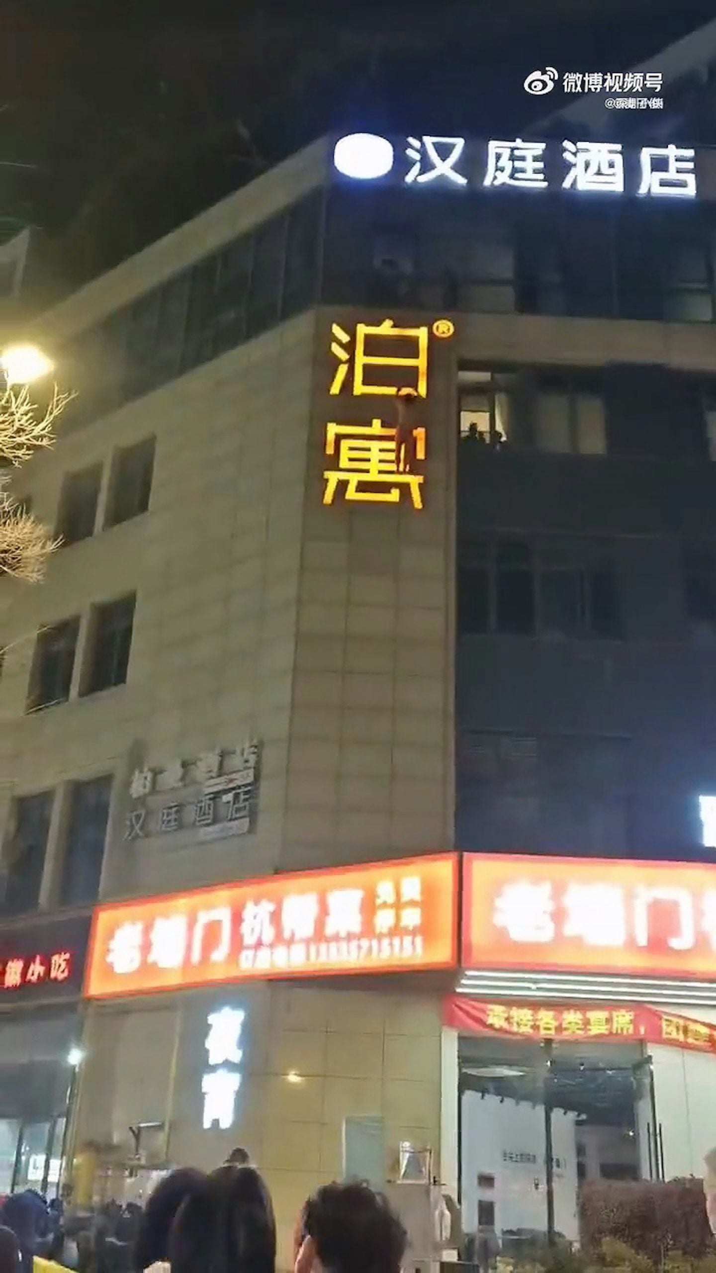 man hanging hotel signboard